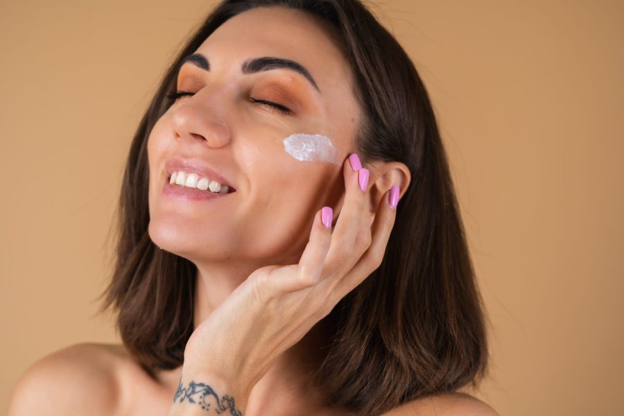 Mulher satisfeita porque está usando primer para preparar sua pele antes da make